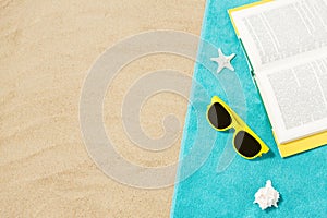 Sunglasses and book on beach towel on sand