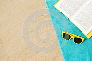 Sunglasses and book on beach towel on sand