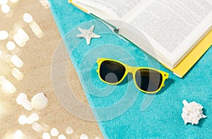 Sunglasses and book on beach towel on sand