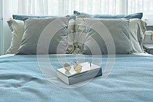 Sunglasses and book setting on bed in blue color scheme decoration