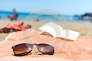 Sunglasses and book on a towel at the beach