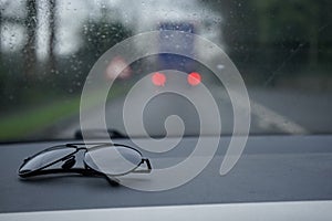 Sunglasses on a car dashboard of rainy holiday