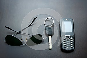 Sunglasses, car key and cellphone on a wooden table