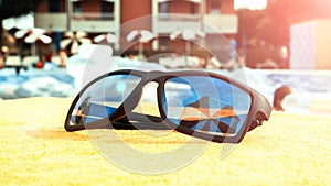 Sunglasses closeup summer background. Beach pool equipment with travel sunglasses on yellow holiday towel. Outdoor relax