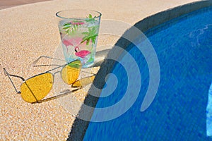 Sunglasses and cold drink on poolside, summer holiday concept
