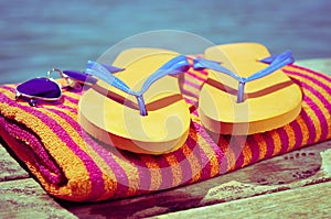 Sunglasses, flip-flops and beach towel, on a wooden boardwalk