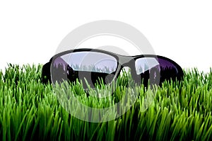 Sunglasses on grass against white