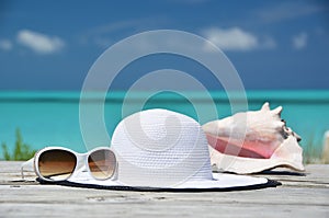 Sunglasses, hat and conch against ocean