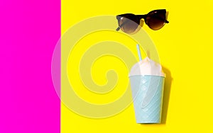 Sunglasses and ice scream cup on neon background