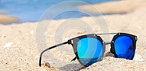 Sunglasses lie on a beach on sand