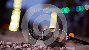 Sunglasses lie on tropical beach and silhouette of young spinning around couple reflected on the background. slow motion