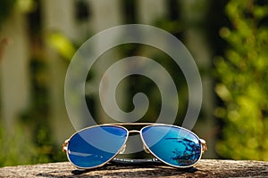Sunglasses lie on a wooden table on a nature background