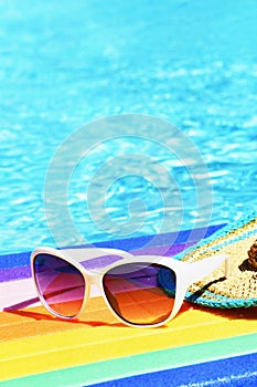 Sunglasses, lilo and hat on the water in hot sunny day. Summer background for traveling and vacation. Holiday idyllic.