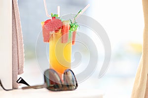 Sunglasses lying near alcoholic cocktail glass on beach closeup