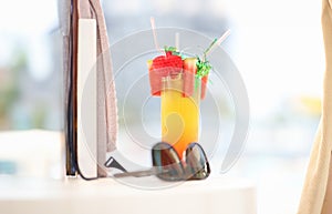 Sunglasses lying near alcoholic cocktail glass on beach closeup