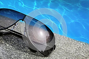 Sunglasses next to a pool