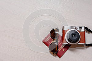 Sunglasses with the passport of a citizen of the Russian Federation and an instant photo camera on a white wooden background