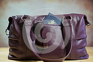 Sunglasses and passport in purple carry bag photo