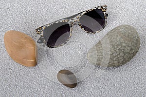 Sunglasses and pebbles on the sand