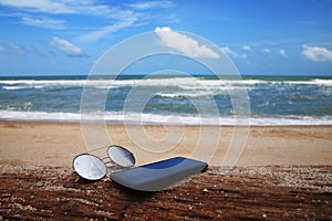 Sunglasses and phone are placed on dry logs and reflections of bright sky