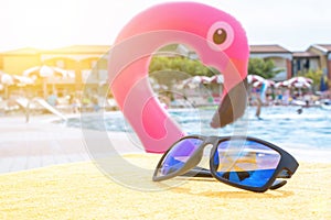 Sunglasses pool summer background. Beach pool equipment with travel sunglasses on yellow holiday towel. Sun glasses near