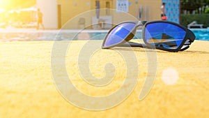 Sunglasses pool summer background. Beach pool equipment with travel sunglasses on yellow holiday towel. Sun glasses near