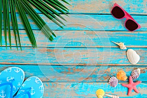 Sunglasses, shells, starfish and slipper on wood background.