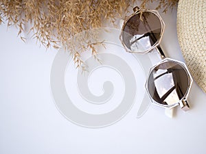 Sunglasses, straw hat and dry grass top view izolated copy paste space