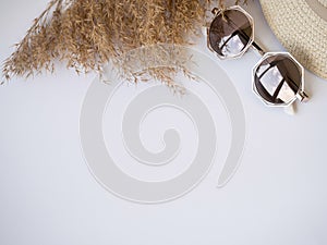 Sunglasses, straw hat and dry grass top view izolated copy paste space