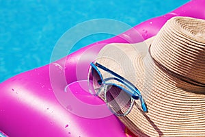 Sunglasses straw hat pink air mattress swimming pool. Tropical concept