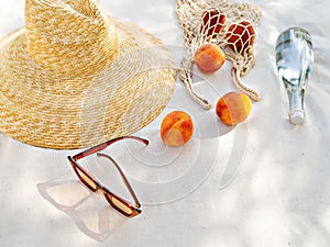 Sunglasses and straw hat on a sea beach with bottle water and fruits.