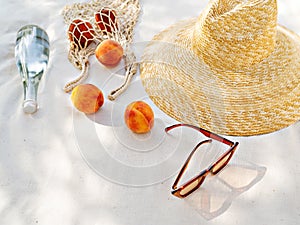 Sunglasses and straw hat on a sea beach with bottle water and fruits.