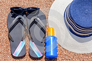 Sunglasses, suntan lotion, Slip slops and sunhat on a tropical beach photo