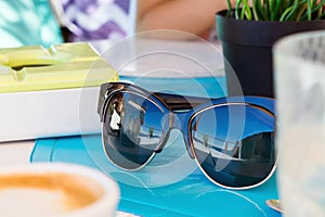 Sunglasses on the table on reflection sea and blue sky