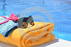 Sunglasses towel and a hat near a swimming pool on a summer day