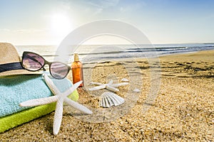 Sunglasses, towels, hat, sun block, shells and starfish on sandy