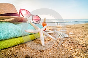 Sunglasses, towels, hat, sun block, shells and starfish on sandy