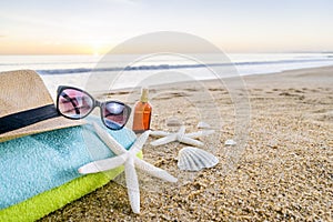 Sunglasses, towels, hat, sun block, shells and starfish on sandy