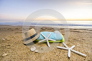 Sunglasses, towels, hat, sun block, shells and starfish on sandy