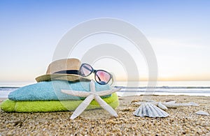 Sunglasses, towels, hat, sun block, shells and starfish on sandy