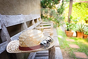 Sunglasses with vintage straw hat fasion on chair, Background for vintage resort hotel photo