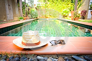 Sunglasses with vintage straw hat fasion on swimming pool, Blur background for vintage resort hotel photo