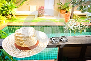 Sunglasses with vintage straw hat fasion on wooden table, Blur background for vintage resort hotel photo