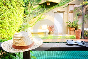 Sunglasses with vintage straw hat fasion on wooden table, Blur background for vintage resort hotel photo