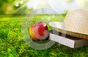 Sunhat, book and fresh apple