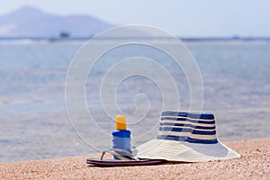 Sunhat, thongs and sunscreen on a beach