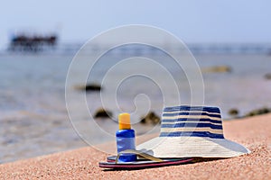 Sunhat, thongs and sunscreen on a beach