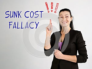 SUNK COST FALLACY exclamation marks phrase on the gray wall