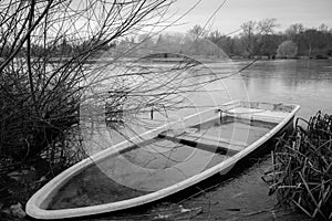 sunken rowing boat lies on the shore of a frozen small lake