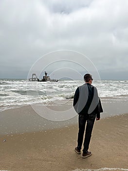 Sunken trawler, shipwreck. Ship Zeila at Skeleton Coast Namibia. Man stands.